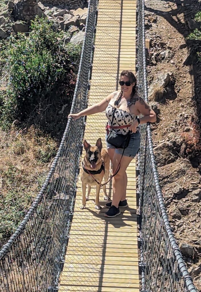 Image of author, Emma Louise Kirkham and her German Shepherd dog on a wooden bridge